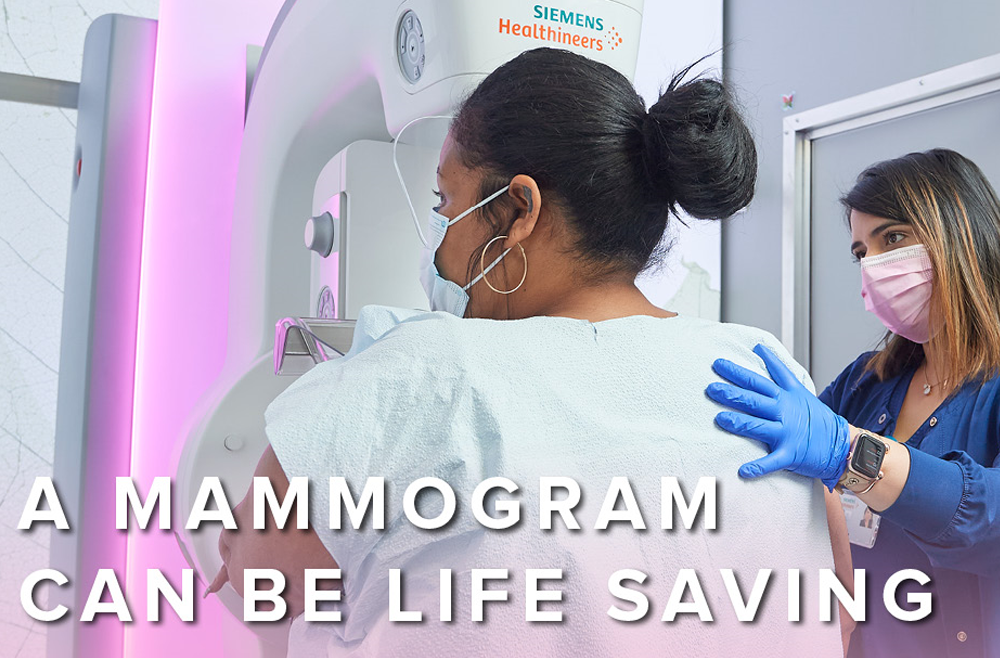 A woman receiving a mammogram stands next to a physician